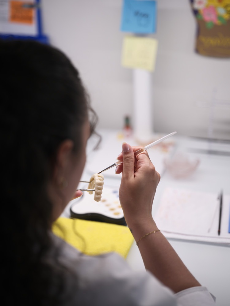 A Woman Is Focused On Writing or Drawing On a Piece of Paper at a Desk.